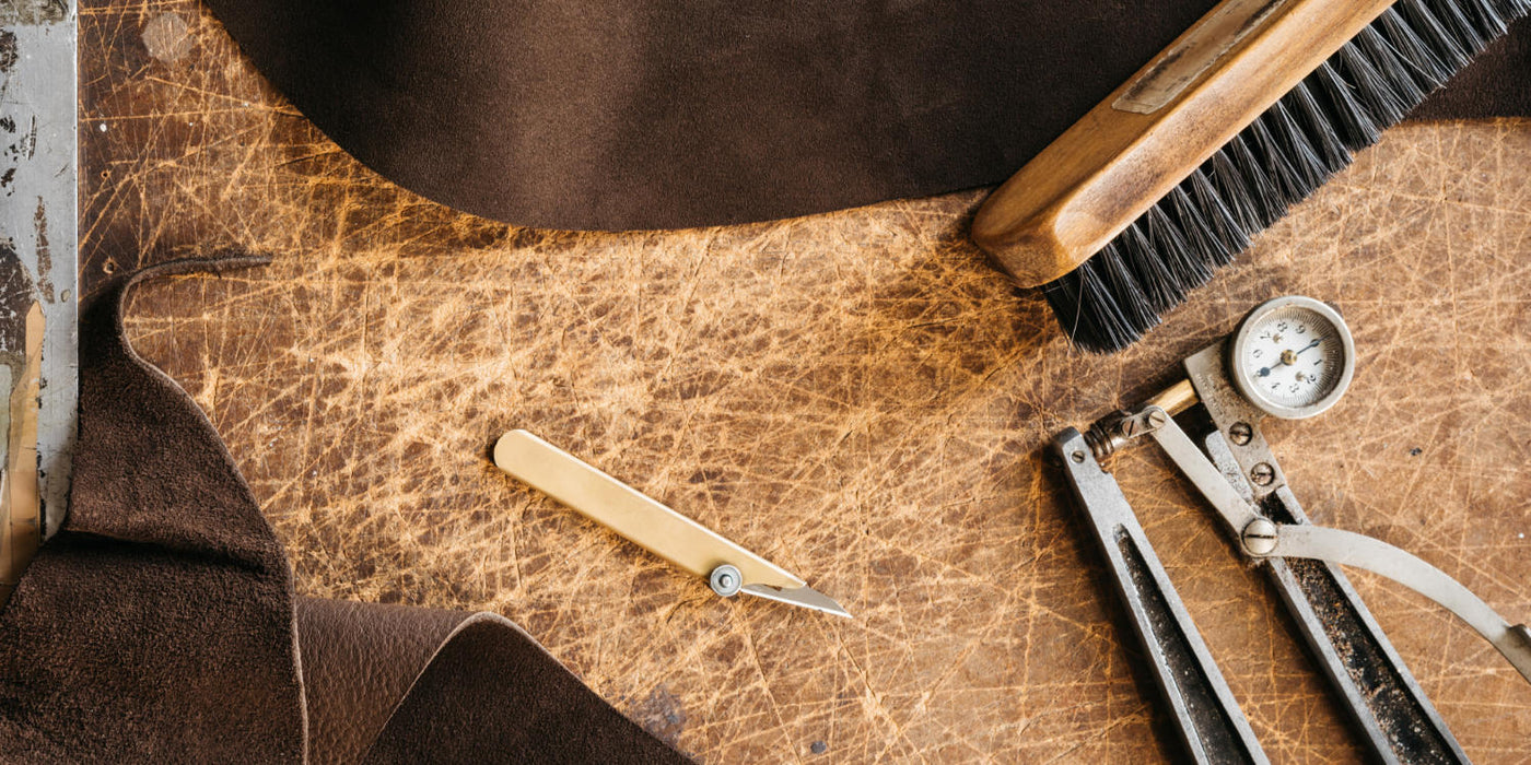 Workshop bench with leather tools for making leather guitar straps | Leather by C/F/ Stead of Leeds, the leather used for the Bison Boa Boutique Series Relic Ready guitar strap | C.F. Stead of Leeds is an ultra premium English tannery.